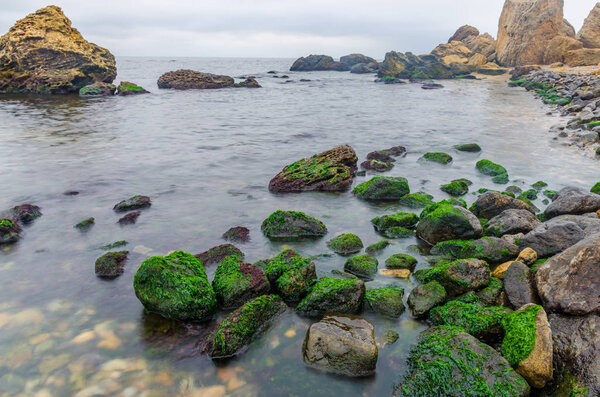 Фотография камня на пляже на длительной экспозиции
