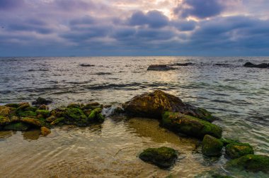Taşlar ile deniz sahilde günbatımı