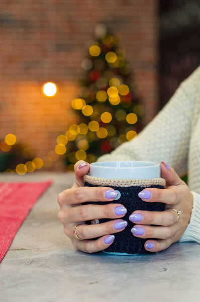 Girl holding a cup with tea on the new year tree background