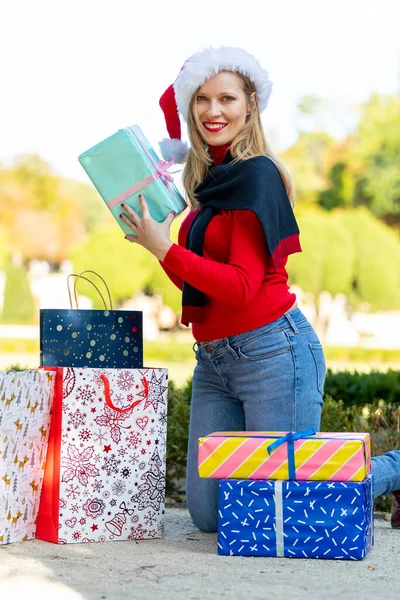 Noel sokaklara dökülür, hediyeler, alışveriş çantaları ve Noel süsleriyle genç bir kadın.