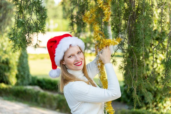 Noel sokaklara dökülür, hediyeler, alışveriş çantaları ve Noel süsleriyle genç bir kadın.