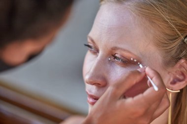 Makyaj sanatçısı inci benzeri makyaj yapıyor.