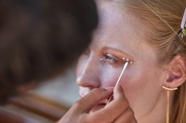 Makyaj sanatçısı inci benzeri makyaj yapıyor.