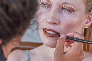 Makyaj sanatçısı inci benzeri makyaj yapıyor.