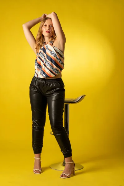 Bella mujer vestida para barra de bar sobre fondo amarillo en actitud decidida y confiada