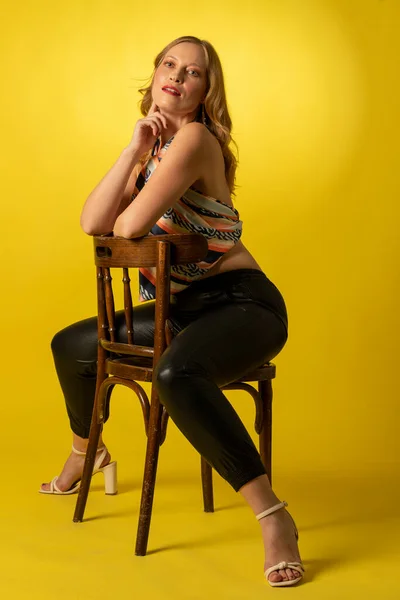 Bella mujer vestida para barra de bar sobre fondo amarillo en actitud decidida y confiada