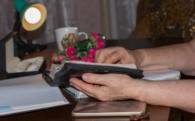 Yaşlı bir kadın lambanın altında kitap okuyor..