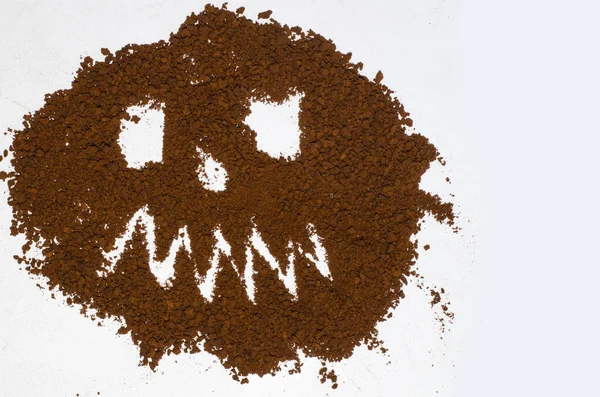 Drawing - a scary face with teeth for Halloween - on a white background filled with instant coffee.
