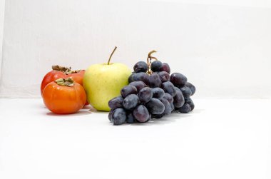 Hayat - sonbahar meyvesi, hurma, yeşil elma, beyaz arka planda siyah üzüm. 