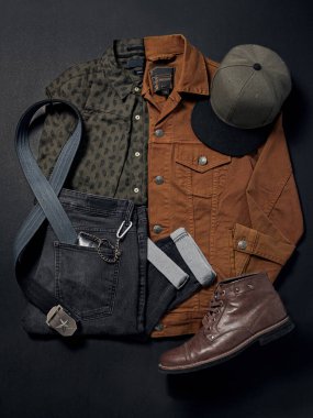 Koyu renk pantolon, yeşil gömlek kahverengi ceket gri kayış kahverengi botlar arka planda siyah kağıt çekim