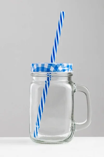 Plaj cam bardağı mavi üst ve mavi pipet beyaz masa üzerinde gri beyaz arka plan