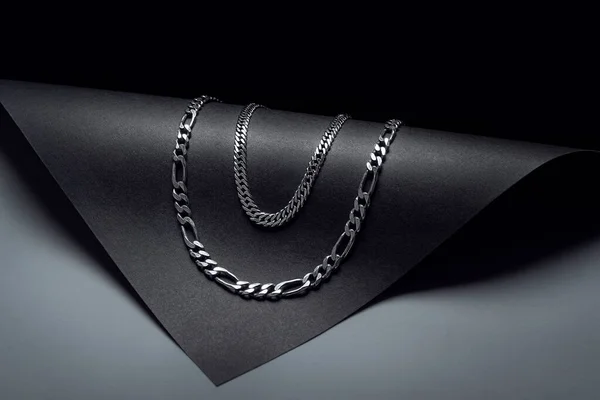 Collar Doble Cadena Plata Sobre Fondo Negro Con Formas Oscuras —  Fotos de Stock