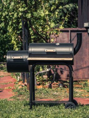 Kapalı kapak ve yazlık önünde yaz bahçesinde duman boru ile silindirik siyah Barbekü görüntülemek