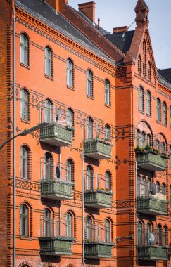 Pencerelerin ve yeşil balkonların bulunduğu Avrupa tarzı binanın tuğla duvarının kırmızı cephesi