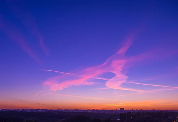 Bulutlar ve Moskova şehir silüetinin panoramik silüeti üzerinde gün batımında Contrails gökyüzünde boyanmış işareti veya glif
