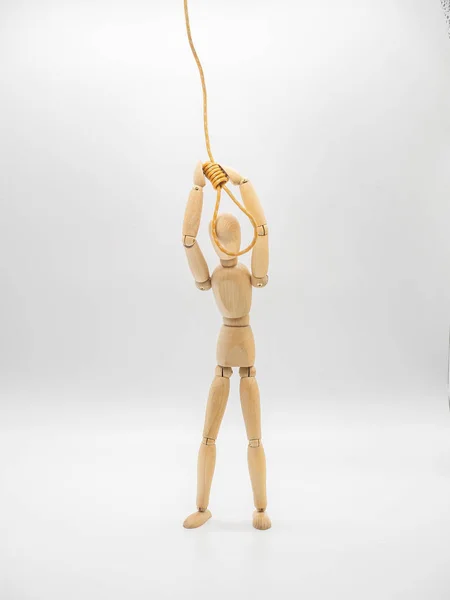 Miniature wooden doll is putting head in the noose of gallows isolated on white. Suicide concept with the hanging rope.