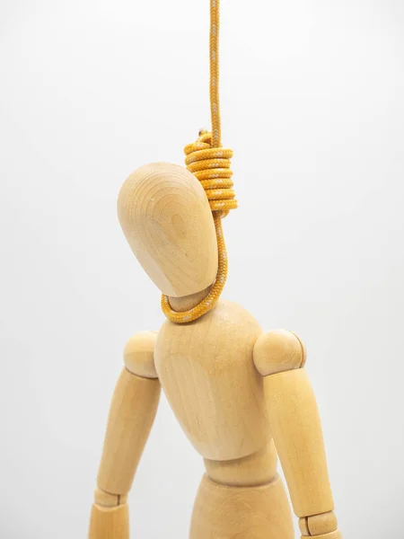Hanged miniature wooden doll with head in the noose of gallows isolated on white. Closeup view.