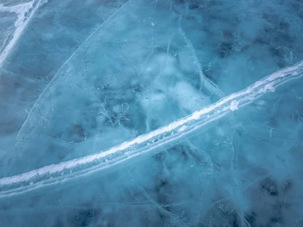 Network of cracks with snow in thick solid layer of ice of a frozen Baikal lake in Siberia (Russia)