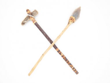 Replicas of the primal stone tools with wooden handles and leather strapping isolated on white background. Crossed primitive stone axe and dagger or spear: weapons of the prehistoric peoples. clipart