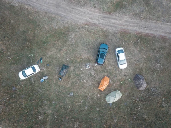 Toprak yol yakınındaki tarlada turist kampı. Yolun yakınındaki çadır ve araçlarla açık alanda kamp kurup havadan aşağıya doğru. Çok renkli turistik kubbeler ve arabalar. Yaz sezonunda ototurizm konsepti.
