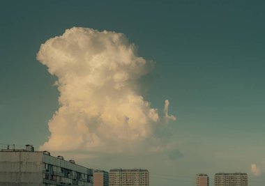 Mavi gökyüzüne karşı tek kümülüs bulutu. Terkedilmiş beyaz büyük bulut, gökyüzündeki apartmanların çatısının üstündeki kuleye benziyor..