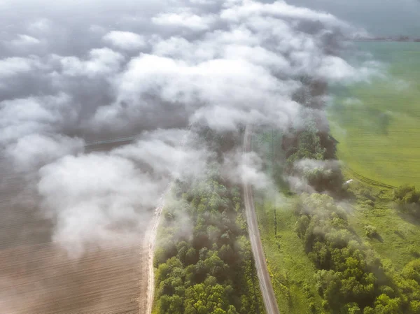 Bulutların kırsal arazi üzerindeki hava manzarası çayırlar, tarımsal alanlar, yollar ve ormanlar. Pastoral arazi üzerinde saydam bulutlar, hava çekimi.