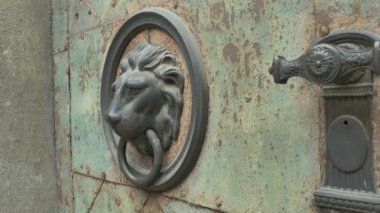 Eski aslan şeklinde kapı tokmağı üzerinde çalan kadın.