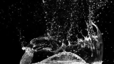 Suyun yavaş hareketi siyah arkaplan üzerine soyut parçacık sıçratır