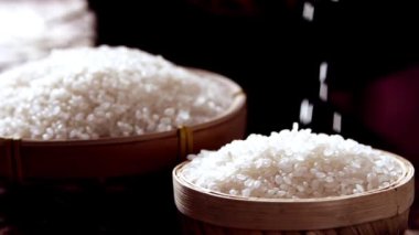 Tahta kaseye dökülen bir yığın Japon pirinç taneleri. Arkaplanda Tehdit Sepetinde Pirinç - Yavaş çekim