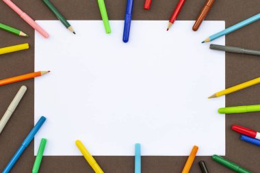 Achildren masasında boş kağıt arkaplanlı renkli kalemler