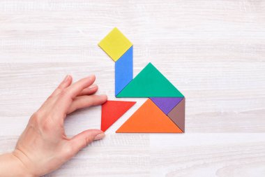 Kişi atış yukarıdan tangram rakamlar evin ahşap masa üzerinde şekil oluşturma.
