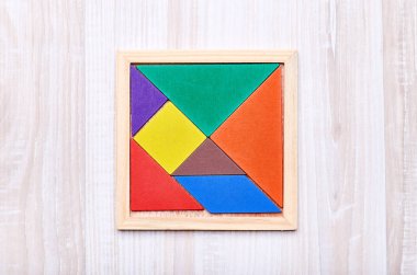 Geometrik şekiller, renkli taşlarla oluşan bir tangram bulmacanın üzerinde hafif bir ahşap adam bir meydanda toplanan