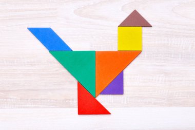 Ahşap masa üzerinde tavuk şeklinde düzenlenmiş renkli tangram şekiller Lay paylamak