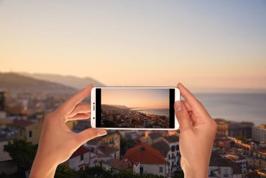 Bir turist gündoğumu zamanlı bir cep telefonu olarak İtalyan sahil kasabası Salerno bir fotoğraf çekici