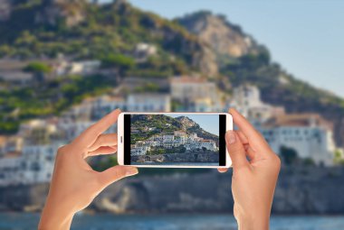 Bir turist bir cep telefonu İtalyan şehirde Amalfi dağda eski İtalyan evleri bir fotoğraf çekici