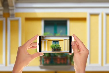 Bir turist merkezi Milano evlerin pencere bir fotoğraf çekici kapattılar ve çiçekler bir cep telefonu ile dekore edilmiş