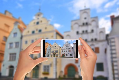 Bir turist binanın fotoğrafını bir cep telefonu eski binalar - üç kardeşler - Riga, Letonya karmaşık alıyor