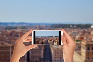 Bir turist bir cep telefonuna Vittorio Emanuele anıt üzerinde Roma gözlem güverteden panoramik bir fotoğraf çekici