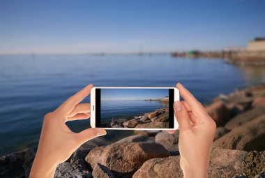Bir turist setin Tallinn Baltık Denizi üzerinde bir fotoğraf üzerinde bir cep telefonu açık yaz akşamı çekici