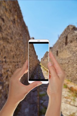 Bir turist eski tarihsel duvar sokak ve Pompei, İtalya için açık mavi gökyüzü bir cep telefonu ile fotoğraf çekme