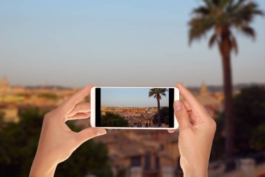 Bir turist bir cep telefonu ön planda sabah Roma palmiye ağacı ile panoramik bir fotoğraf çekici