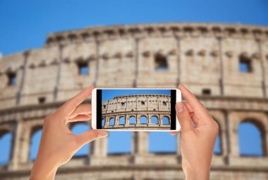 Bir turist bir cep telefonu mavi gökyüzü Roma, İtalya karşı Colosseum bir fotoğraf çekici