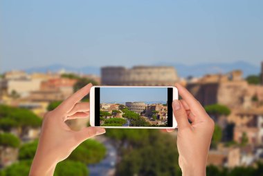 Bir turist Roma manzarası colosseum mavi gökyüzü ile fotoğrafını cep telefonu yaz gününde atıyor