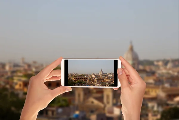 A tourist is taking a photo of Rome skyline sunrise with clear blue sky on a mobile phone