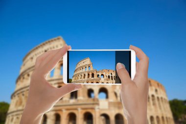 Bir adam Colosseum bir fotoğraf mavi gökyüzüne karşı bir cep telefonu Roma, Italya'yapıyor