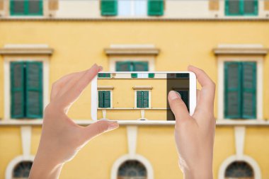 Bir adam--dan pencere eşiği bir Roma, İtalya binaların üstünde hareket eden telefon ve cephe desen resmini yapıyor