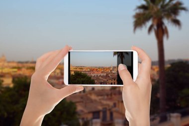 Bir adam sabah Roma palmiye ağacı ile panoramik bir fotoğraf bir cep telefonu ön planda yapıyor