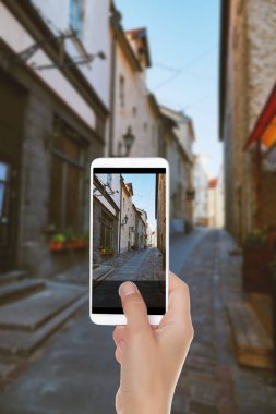 Bir adam küçük bir Avrupa fotoğrafını Tallinn, Estonya eski bölümü bir cep telefonuna sokak yapıyor