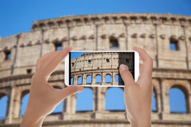 Bir adam bir cep telefonu mavi gökyüzü Roma, İtalya, karşı bir fotoğraf Colosseum yapıyor