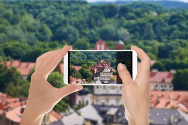 Bir adam bir fotoğraf bir cep telefonuna Saint Francis Assisi kilisenin bir manzaralı, Vilnius Panoraması yapıyor